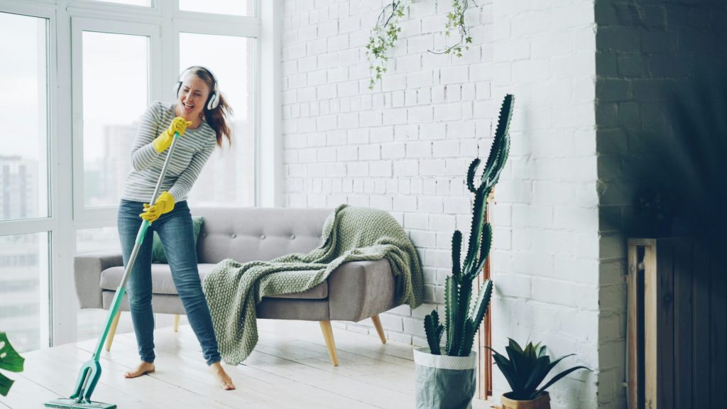 Woman singing and dancing while vacuuming a room