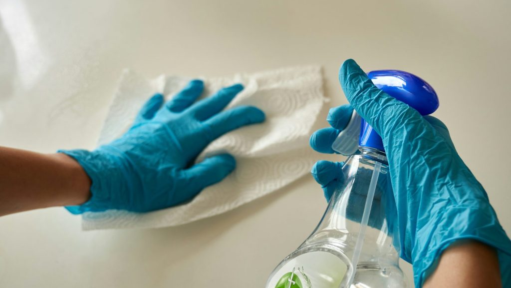person holding blue textile near clear glass bottle